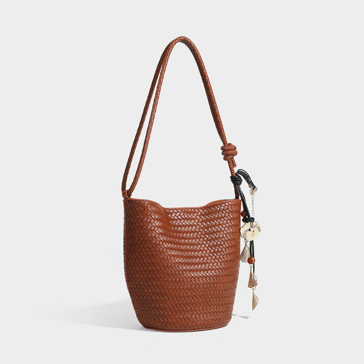 Olive green woven leather-look bucket bag with braided crossbody strap, knotted adjustment, and gold-tone tassel charm with