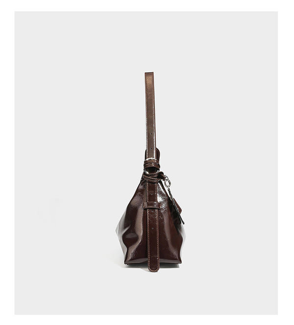 Glossy dark brown hobo shoulder bag with slim strap, front zip pocket, stud detail, and detachable leopard-print heart charm