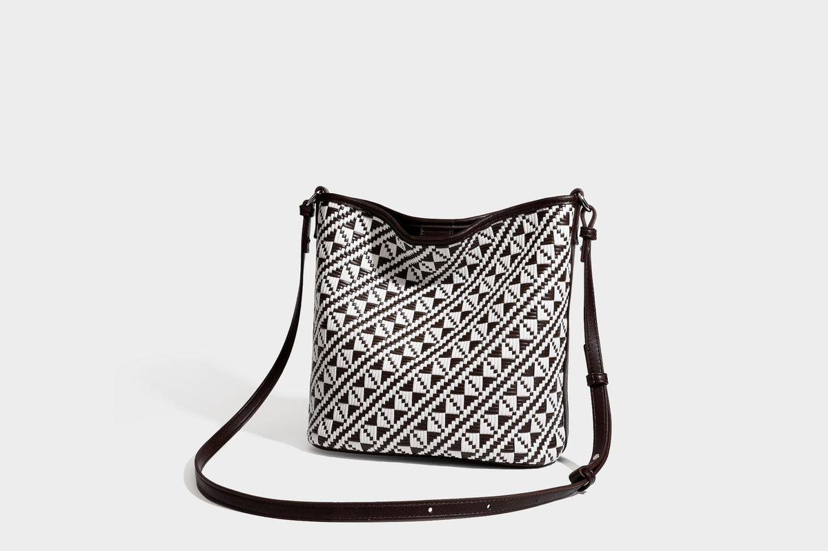 Geflochtene Schultertasche mit geometrischem Ethno-Muster, Besatz in dunkelbrauner Lederoptik, langem verstellbarem Träger und kleinem hängendem Reißverschluss