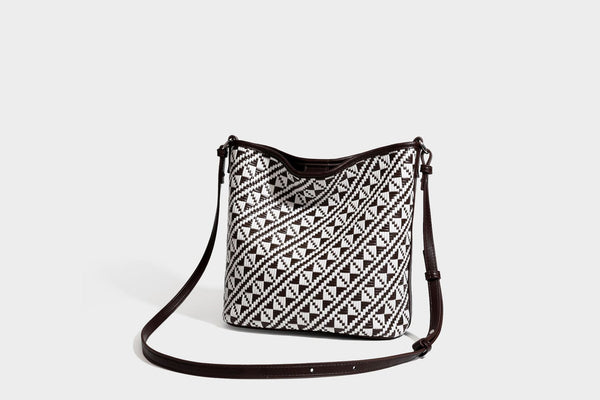Geflochtene Schultertasche mit geometrischem Ethno-Muster, Besatz in dunkelbrauner Lederoptik, langem verstellbarem Träger und kleinem hängendem Reißverschluss