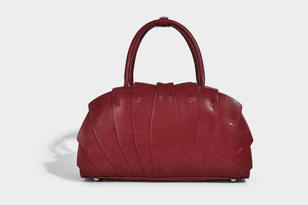 Structured dome satchel with fan-pleated leather-look exterior, dual top handles, and detachable shoulder strap, detail view