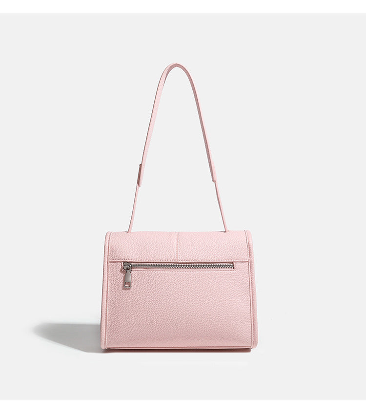 Compact structured flap satchel bag with pebbled texture, snap closure, front strap tabs, and long adjustable crossbody