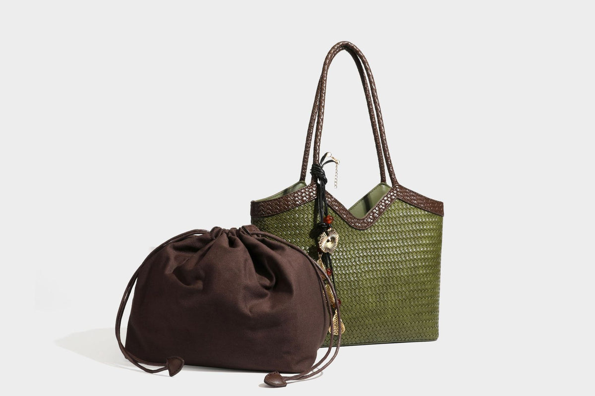 Olivgrüne Tote-Bag in Korbgeflecht-Optik mit dunkelbraunen geflochtenen Schulterriemen, seitlichen Kordelzügen und Perlenanhänger in Goldoptik