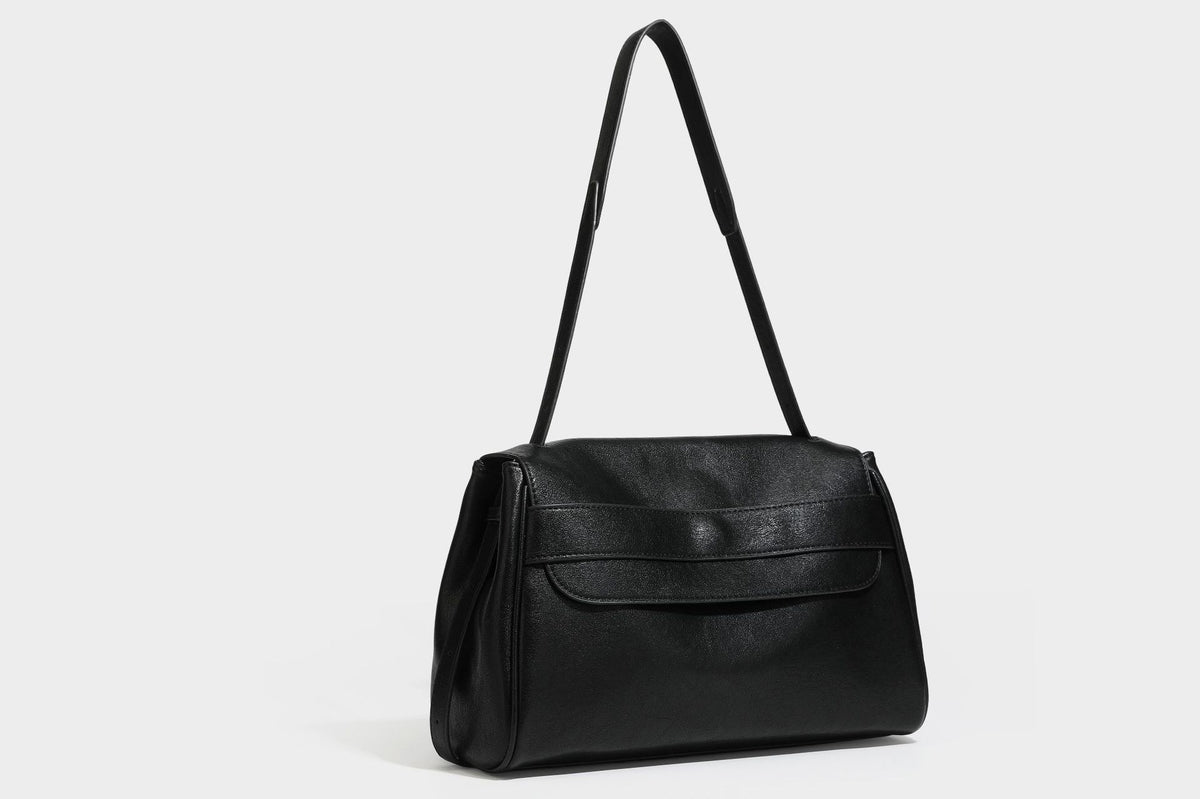 Strukturierte rechteckige dunkelbraune Schultertasche in Lederoptik mit Klappe, mehrlagigem Detail auf der Vorderseite und langem verstellbarem Riemen, Detailansicht