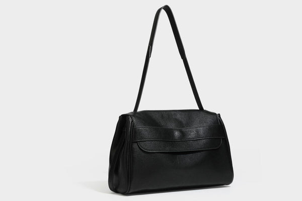 Strukturierte rechteckige dunkelbraune Schultertasche in Lederoptik mit Klappe, mehrlagigem Detail auf der Vorderseite und langem verstellbarem Riemen, Detailansicht