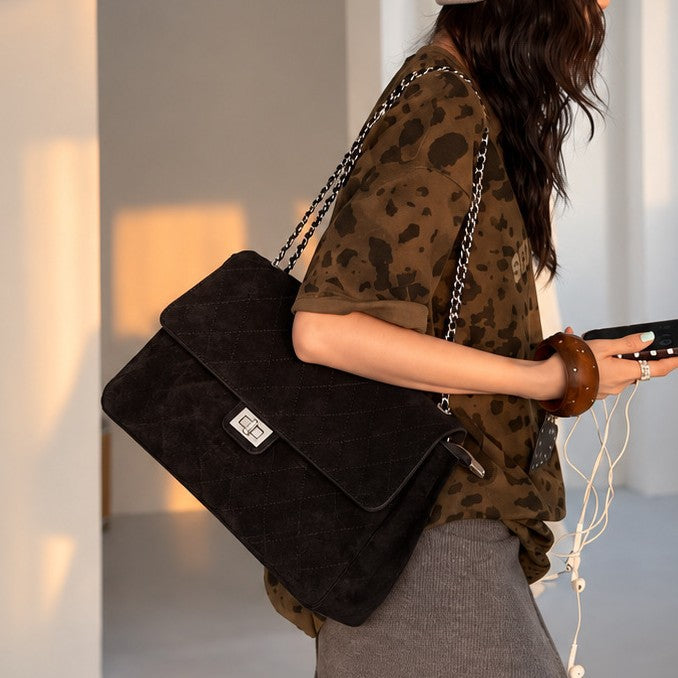 Quilted diamond-stitch flap shoulder bag with double silver chain strap and turn-lock closure in suede-look finish, detail
