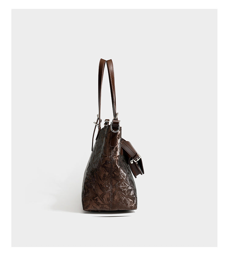 Glossy crinkled metallic-finish tote bag in brown with smooth leather-look top handles, silver-tone hardware, and attached