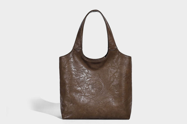 Large open-top tote bag with crinkled leather-look finish, long double shoulder straps, and embossed circular detail on