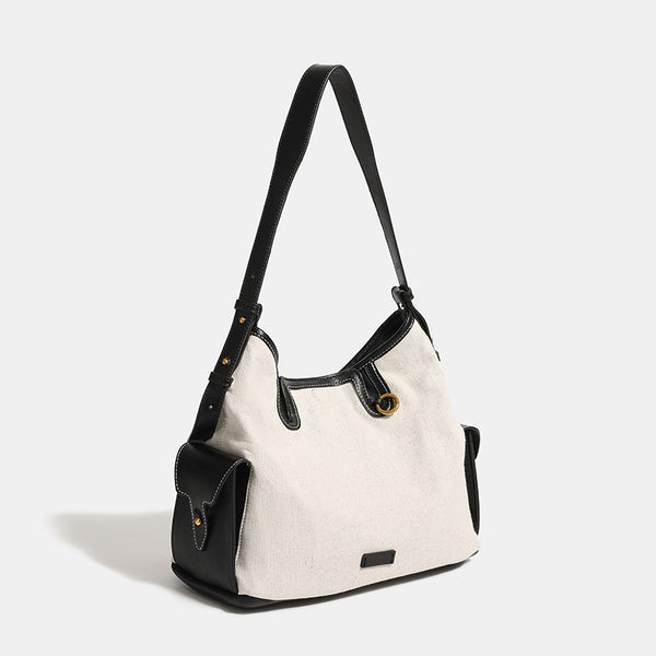 Off-white canvas hobo shoulder bag with black leather-look trim, gold-tone ring hardware, top zip closure, side pockets, and