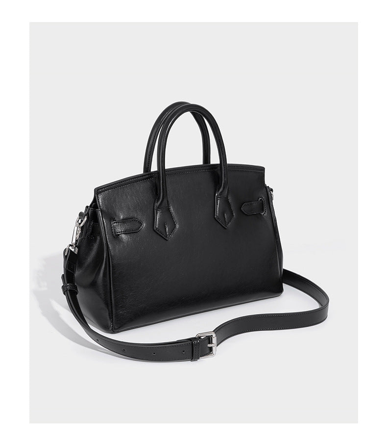 Structured black leather-look satchel bag with silver padlock hardware, front zip pockets, key charms, and top handles