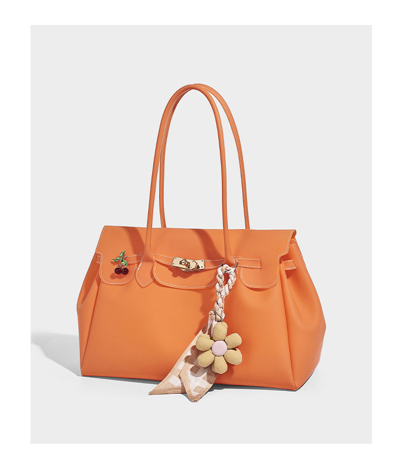 Strukturierte matte Jelly-Tote-Bag mit goldfarbenem Drehverschluss an der Klappe, zwei Schulterriemen, seitlichen Einsätzen und dekorativen