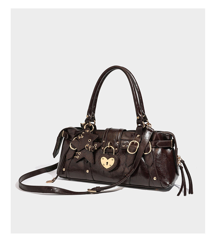 Glossy dark brown structured Boston satchel with heart-shaped lock charm, star pendant, rivet studs, multi-strap front panel