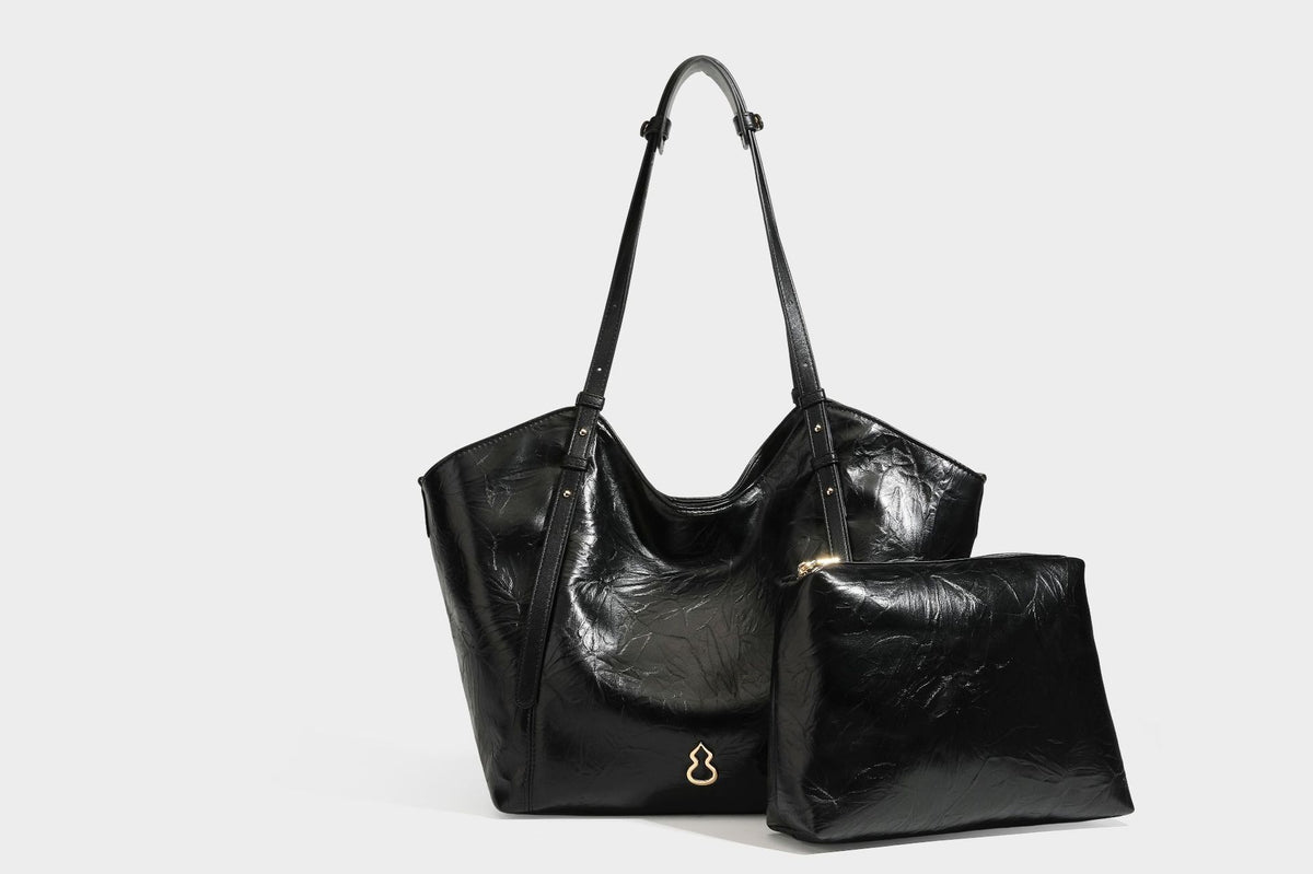 Große, glänzende Tote-Bag aus schwarzem Lederimitat mit geknitterter Optik, lässig fallender Trapezsilhouette, zwei Schulterriemen und goldfarbenen