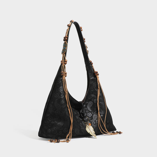 Slouchy boho hobo shoulder bag in embossed brown suede-look finish with beaded strap, cord tassels, and brass-tone leaf