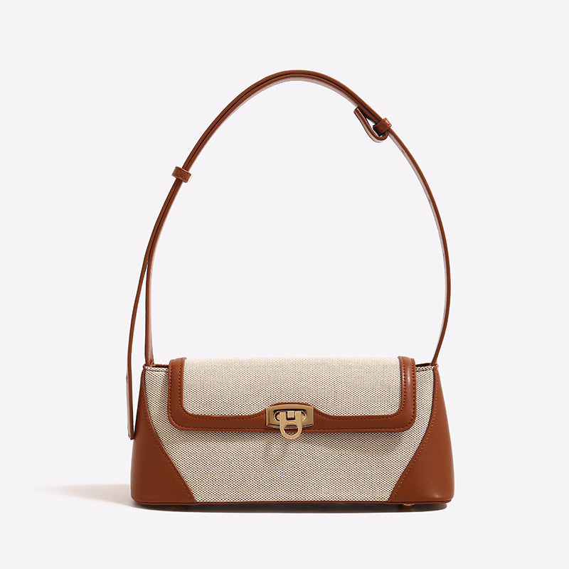 Structured trapezoid flap shoulder bag with canvas-textured body, smooth contrast trim, and gold-tone turn-lock clasp, detail