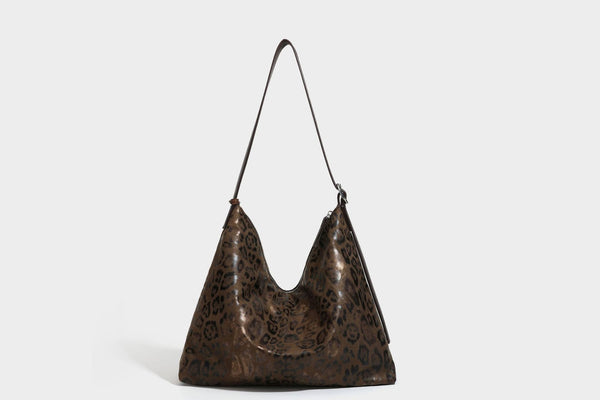 Slouchy leopard print hobo shoulder bag with glossy coated finish, top zipper closure, dark brown trim, and dangling charm