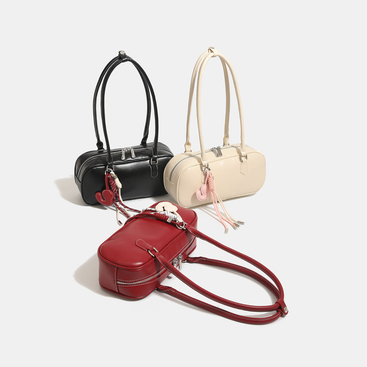 Compact rounded baguette shoulder bag with smooth leather-look finish, slim double straps, silver-tone zipper hardware, and