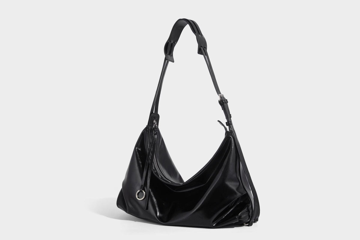 Glossy black slouchy hobo shoulder bag with zip closure, silver-tone ring hardware, and adjustable crossbody strap, detail