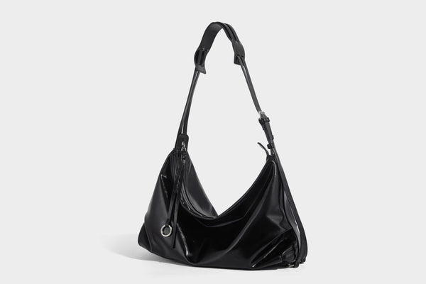 Glossy black slouchy hobo shoulder bag with zip closure, silver-tone ring hardware, and adjustable crossbody strap, detail