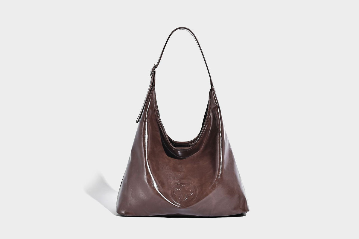 Glossy slouchy hobo shoulder bag with adjustable strap and embossed floral emblem, detail view 16