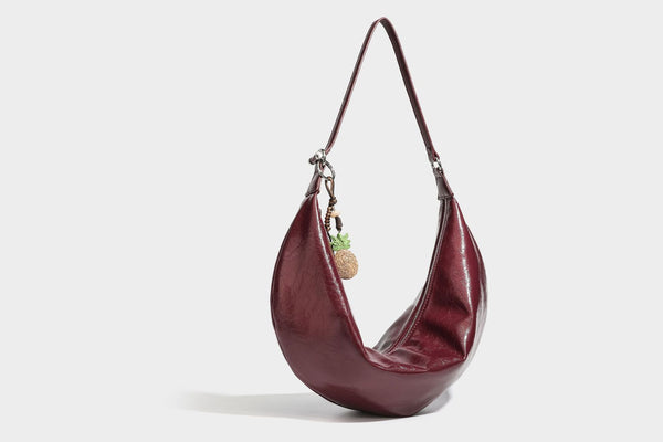 Lässig fallende Hobo-Schultertasche in Halbmondform mit glänzender, geknautschter Lederoptik, schmalem Riemen, silberfarbenen Ringbeschlägen und