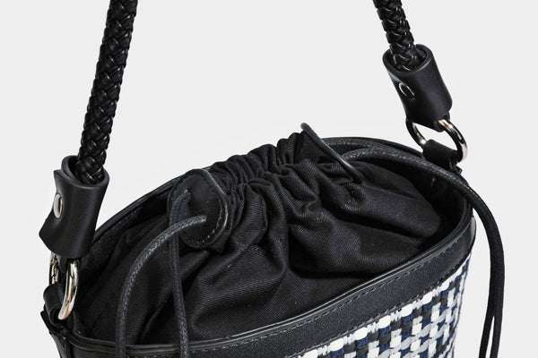 Small structured woven checker bucket bag with braided top handle, drawstring closure, and silver-tone hardware in black