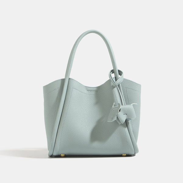 Small structured pebbled leather-look bucket tote bag with bow charm tie closure and gold-tone hardware, detail view 8