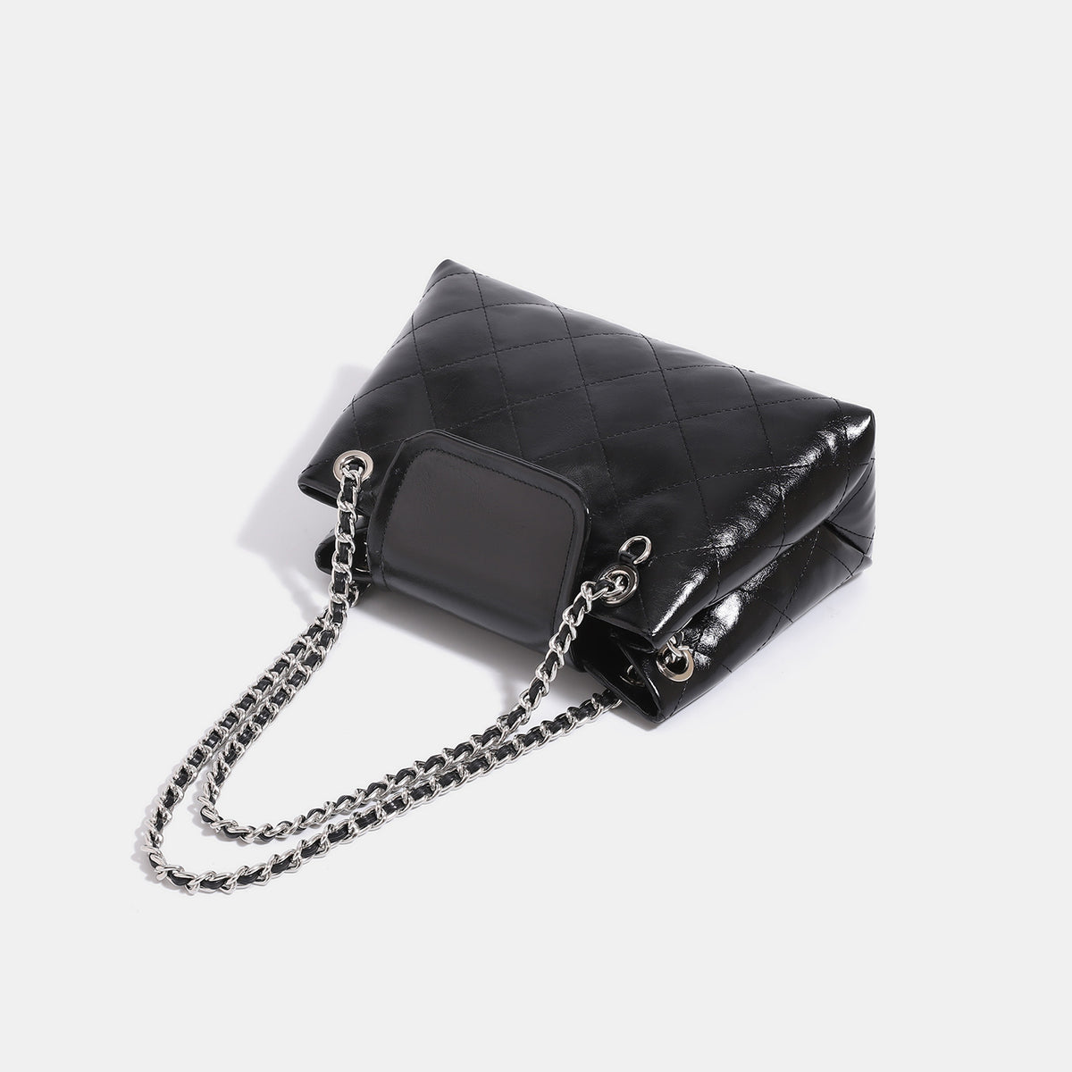 Quilted trapezoid shoulder bag with chain straps, flap closure, and ring hardware, detail view 4