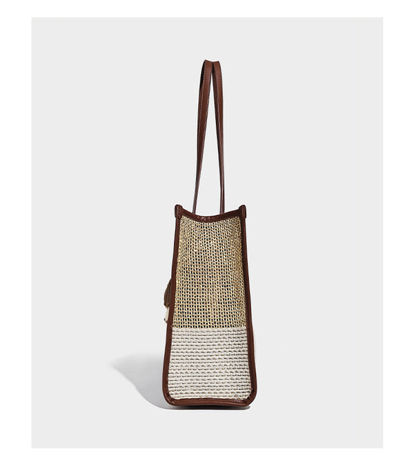 Two-tone woven straw tote bag with leather-look brown trim, long shoulder straps, and knotted tassel charm, detail view 11
