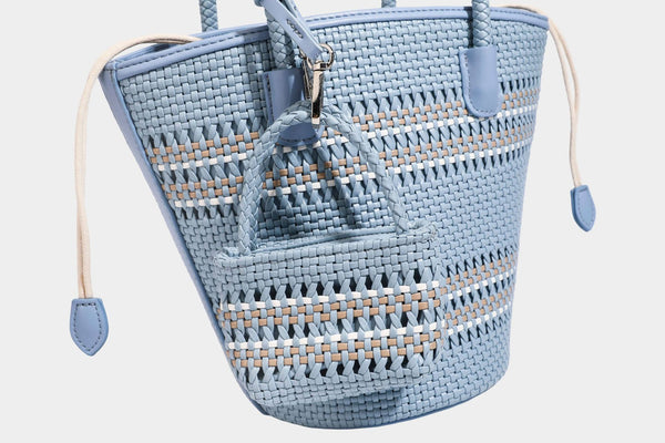 Light blue open-weave woven bucket tote bag with long braided shoulder straps, drawstring side ties, and attached mini pouch