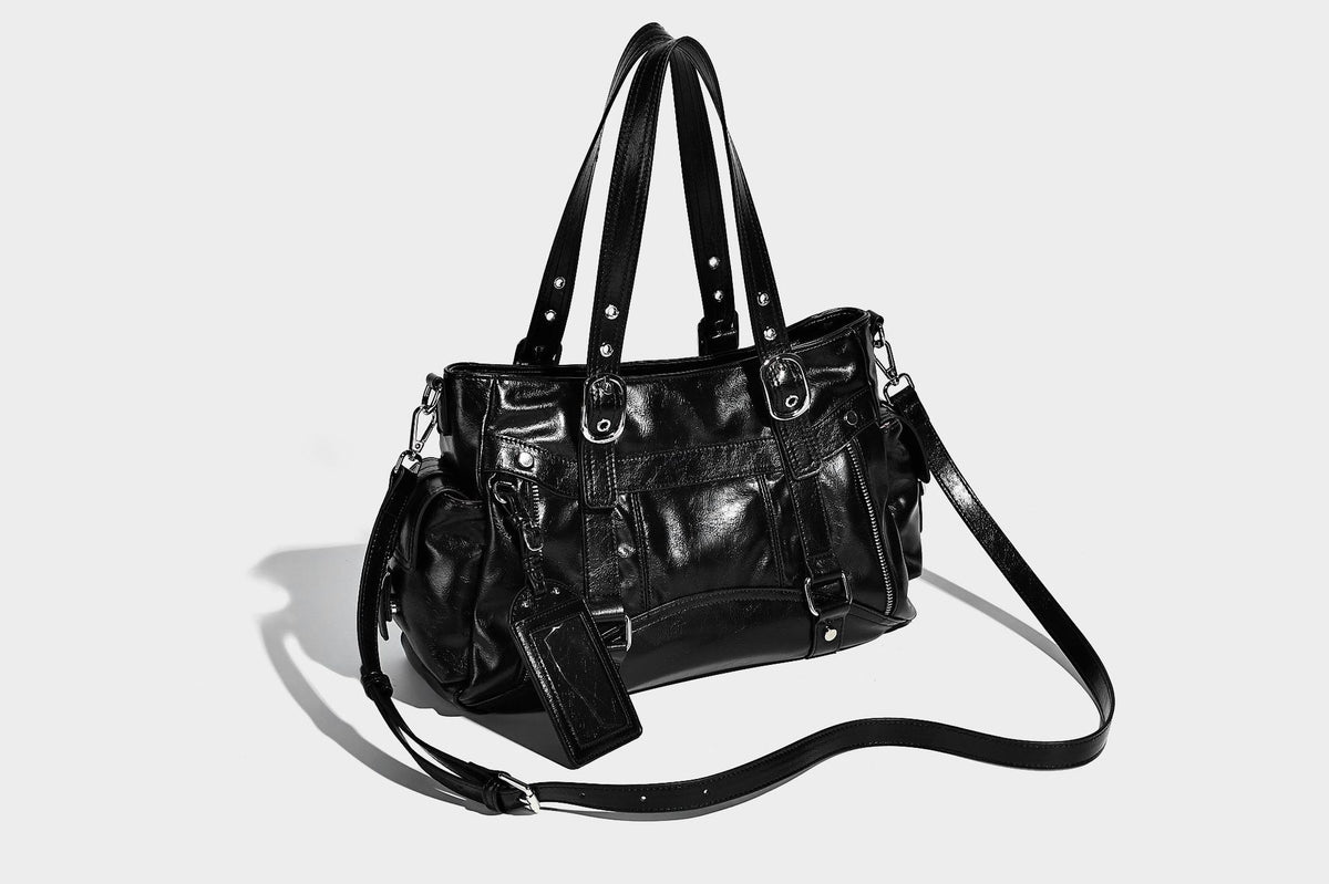 Glossy structured black tote shoulder bag with silver buckle hardware, zip pockets, dual top handles, and detachable, detail