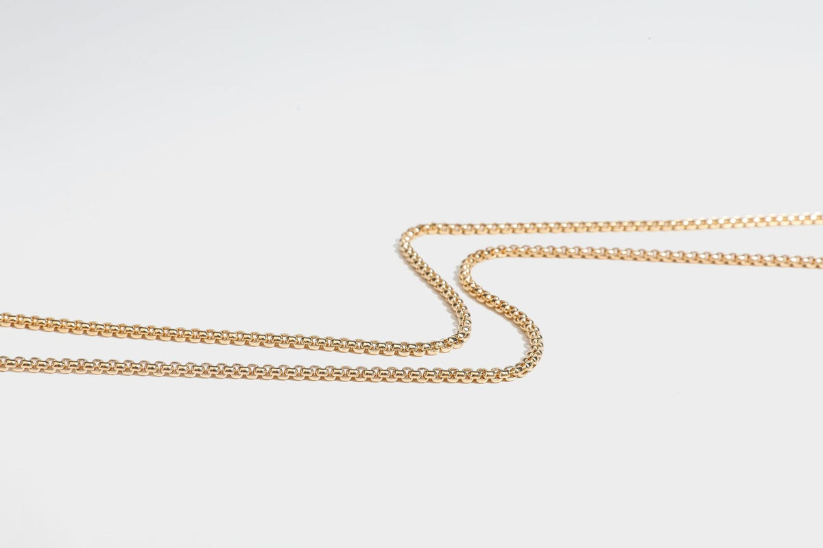 Small structured rectangular metallic woven-texture clutch bag with jeweled knob clasp and gold-tone chain strap, detail view