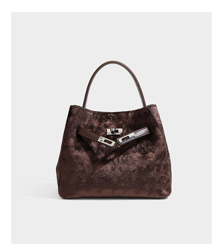 Small structured bucket satchel in embossed velvet-texture fabric with silver turn-lock hardware, rounded top handle, and
