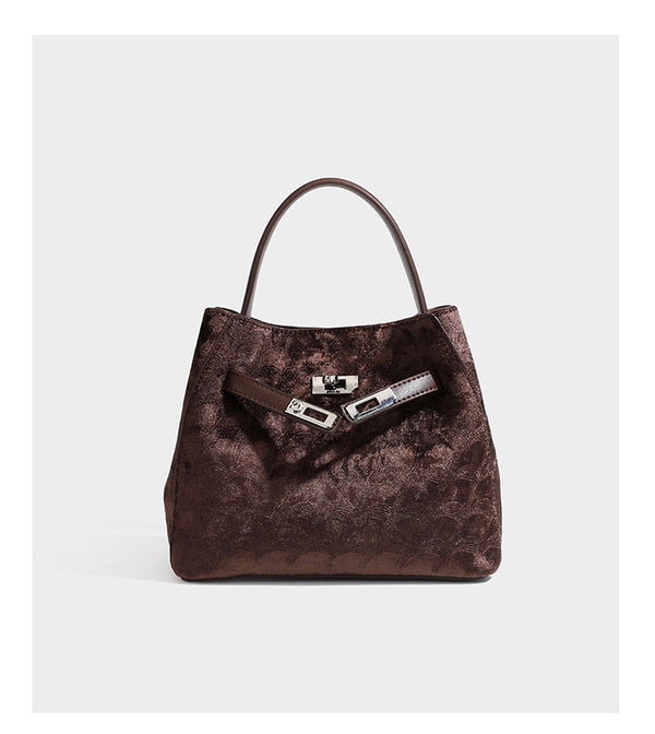 Small structured bucket satchel in embossed velvet-texture fabric with silver turn-lock hardware, rounded top handle, and