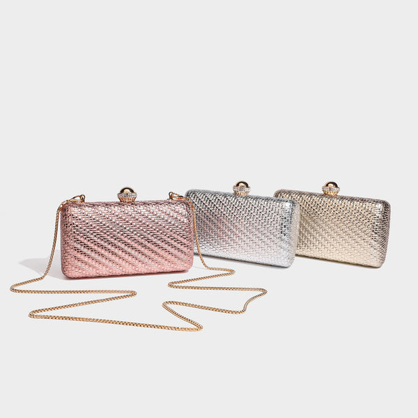 Small structured metallic woven-texture box clutch bag with jeweled kiss-lock dome clasp and slim gold chain strap, detail