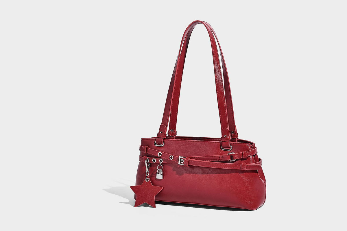 Structured glossy leather-look shoulder bag with wraparound belt straps, silver-tone hardware, and dangling star charm