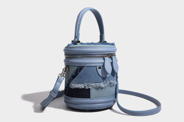 Mini cylindrical barrel bucket bag in denim patchwork with frayed edges, smooth leather-look trim, zip-around top closure