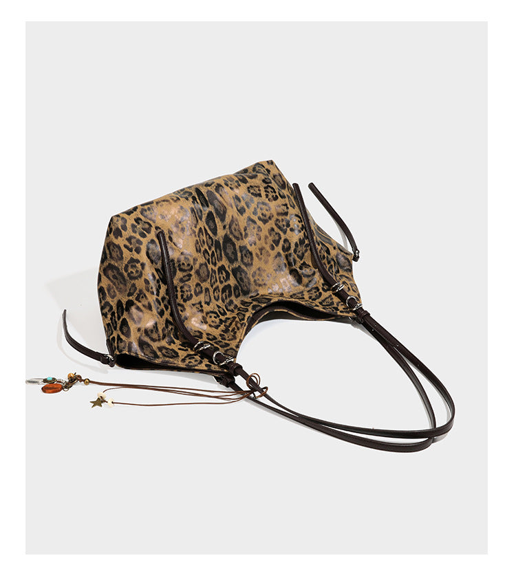 Slouchy leopard-print shoulder tote bag in tan and brown with long double straps, side tie straps, and dangling charm, detail