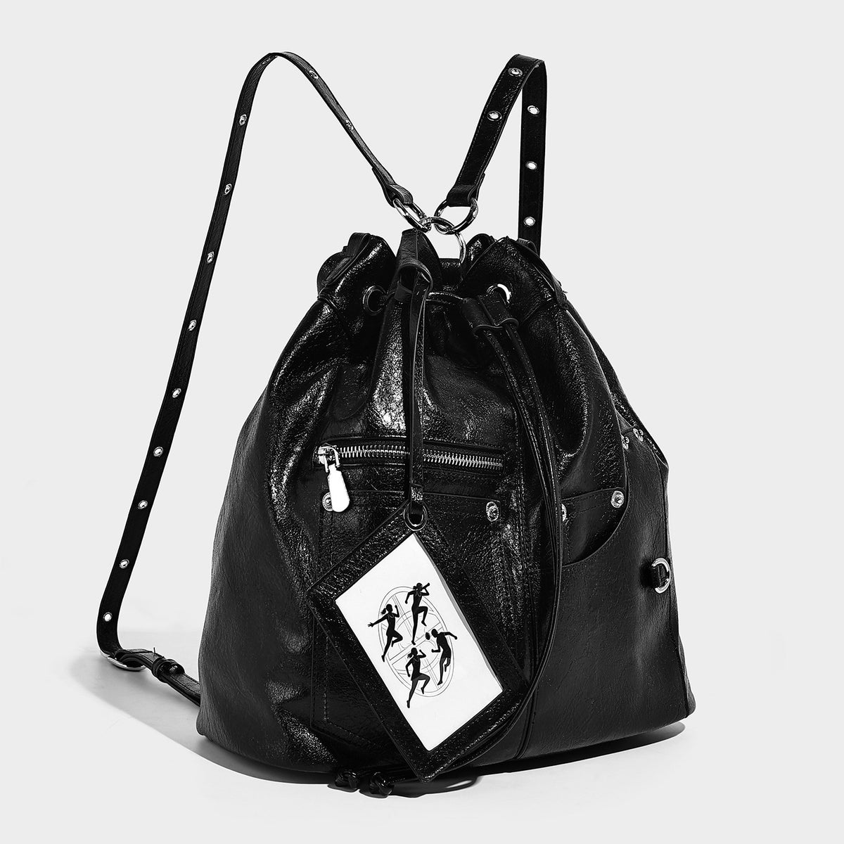 Glossy black convertible bucket backpack with silver grommet-studded straps, drawstring cinch closure, and front zip pocket