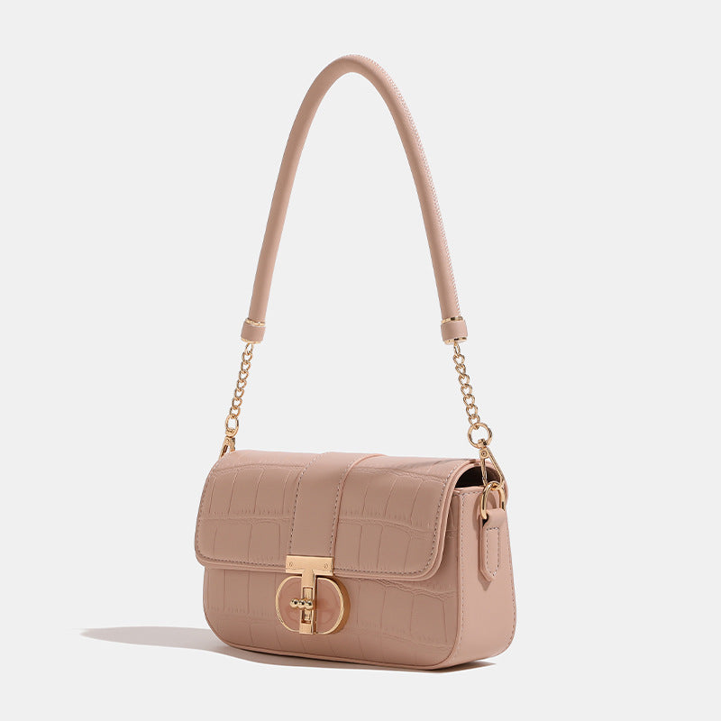 Small structured crocodile-embossed flap shoulder bag with circular gold turn-lock closure and chain-accent strap, detail
