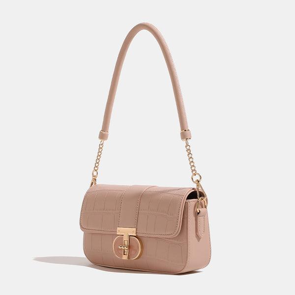 Small structured crocodile-embossed flap shoulder bag with circular gold turn-lock closure and chain-accent strap, detail