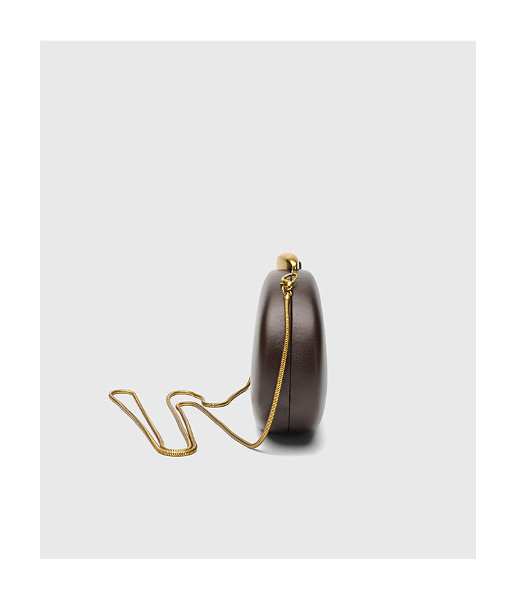 Oval hard-shell crossbody clutch bag with smooth matte leather-look finish and gold-tone snake chain strap, detail view 10