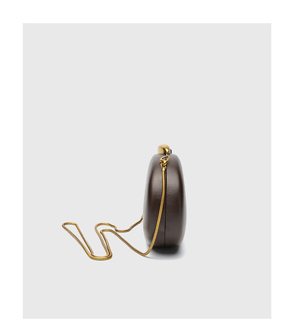 Oval hard-shell crossbody clutch bag with smooth matte leather-look finish and gold-tone snake chain strap, detail view 10
