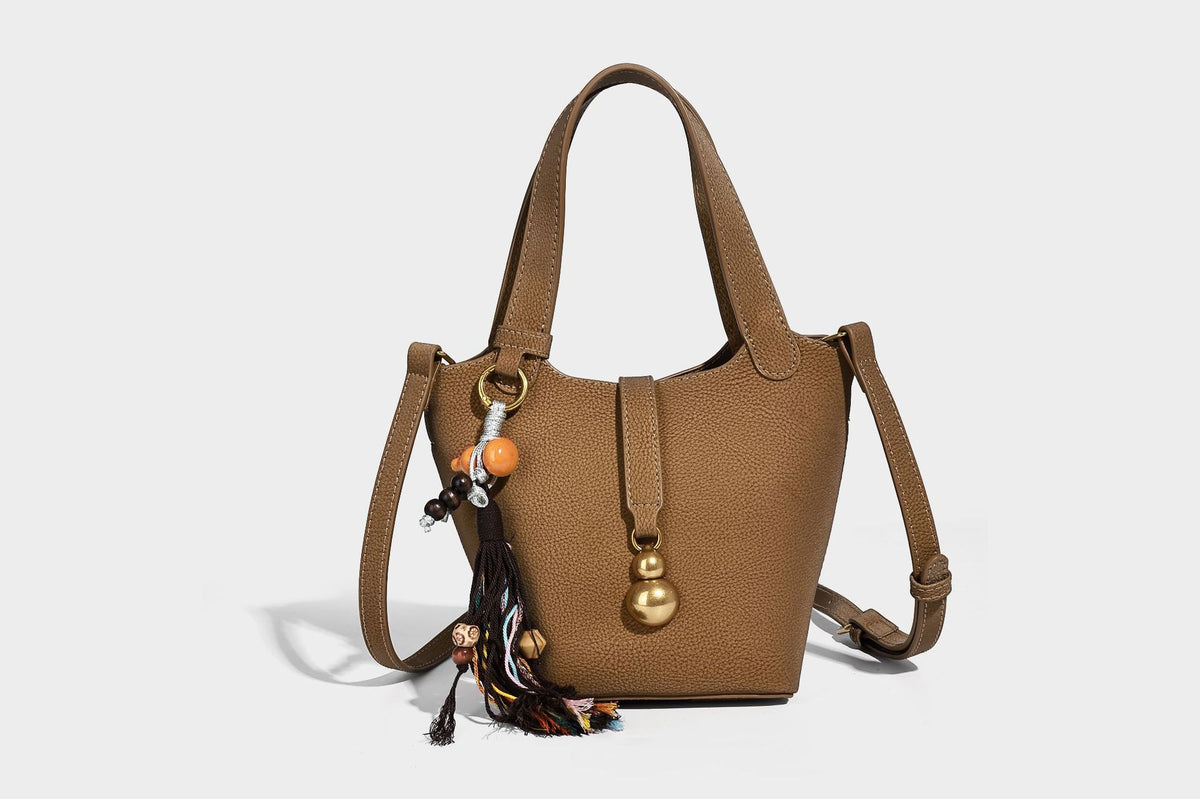 Kleine matte Beuteltasche mit genarbter Oberfläche, antikgoldfarbenen Ringbeschlägen, Perlen- und Quastenanhänger, kurzen Tragegriffen oben und