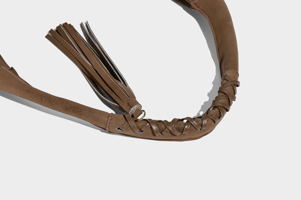 Slouchy crescent hobo bag in matte brown suede-like finish with gold-tone studs, grommets, braided top handle, tassel side