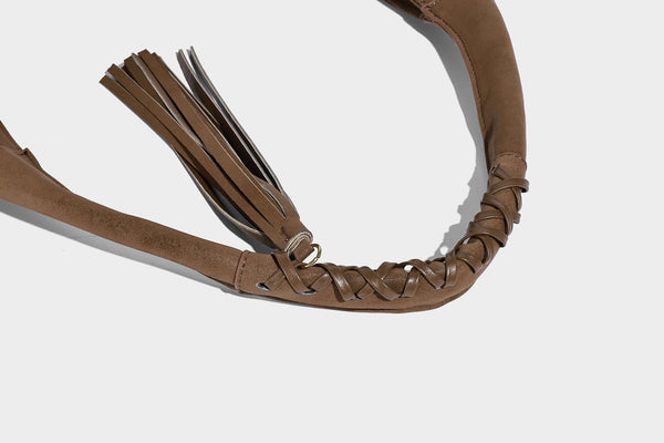 Slouchy crescent hobo bag in matte brown suede-like finish with gold-tone studs, grommets, braided top handle, tassel side
