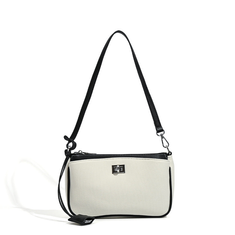 Small structured cream crossbody bag with contrast leather-look trim, silver-tone turn-lock hardware, and adjustable