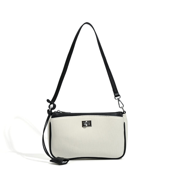Small structured cream crossbody bag with contrast leather-look trim, silver-tone turn-lock hardware, and adjustable
