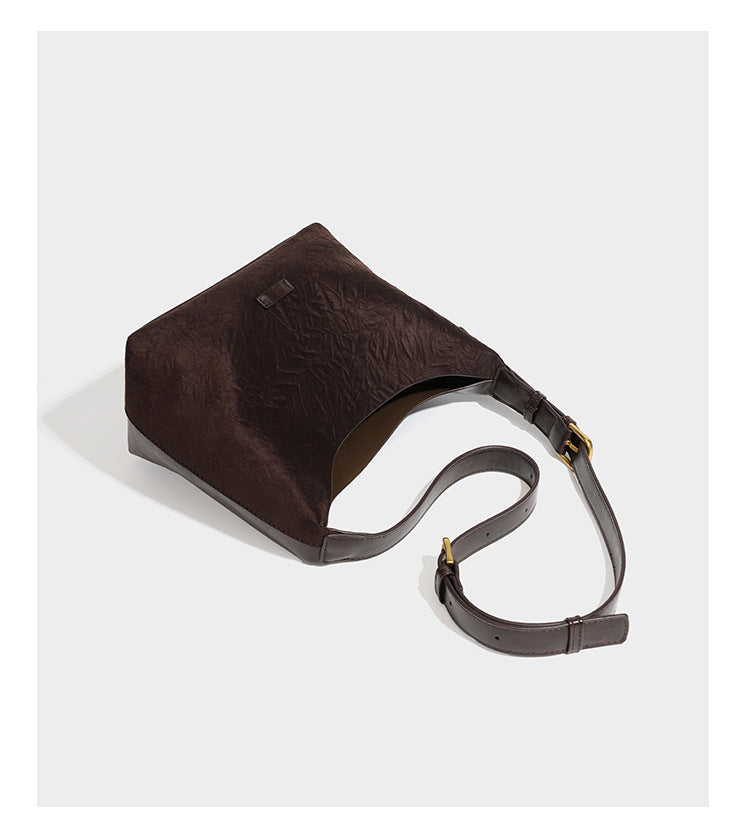 Dunkelbraune, lässig fallende Hobo-Schultertasche mit velourslederähnlich strukturierter Oberfläche, glatter lederähnlicher Paspelierung und Details in Antikgoldoptik, Detailansicht