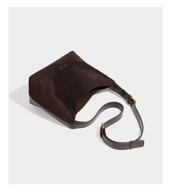 Dunkelbraune, lässig fallende Hobo-Schultertasche mit velourslederähnlich strukturierter Oberfläche, glatter lederähnlicher Paspelierung und Details in Antikgoldoptik, Detailansicht